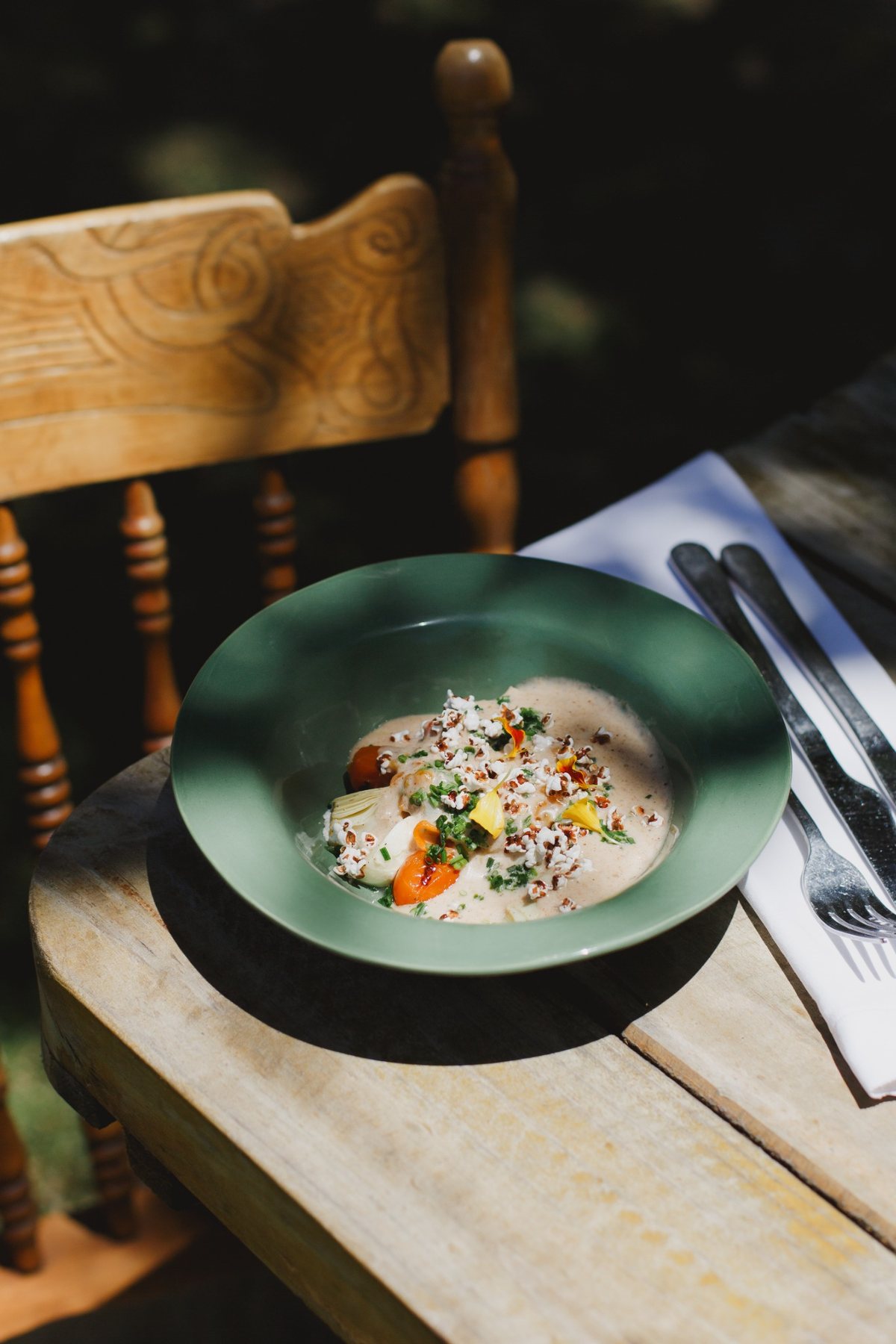 A starter finished with herbs and flowers, served in a green ceramic bowl
